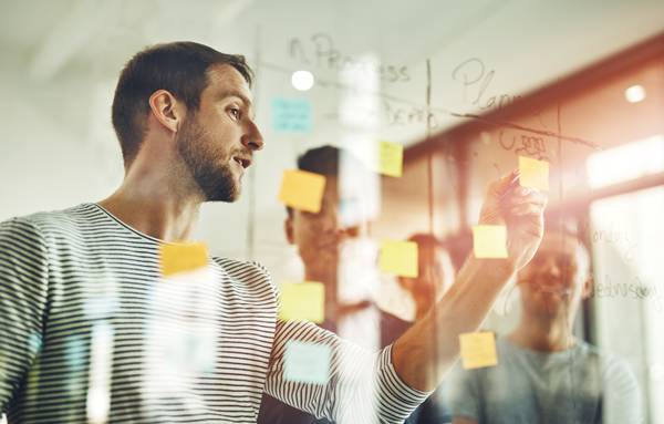Aprendo – Mitarbeiter planen am Lightboard schreibend ihre nächsten Phasen und Features
